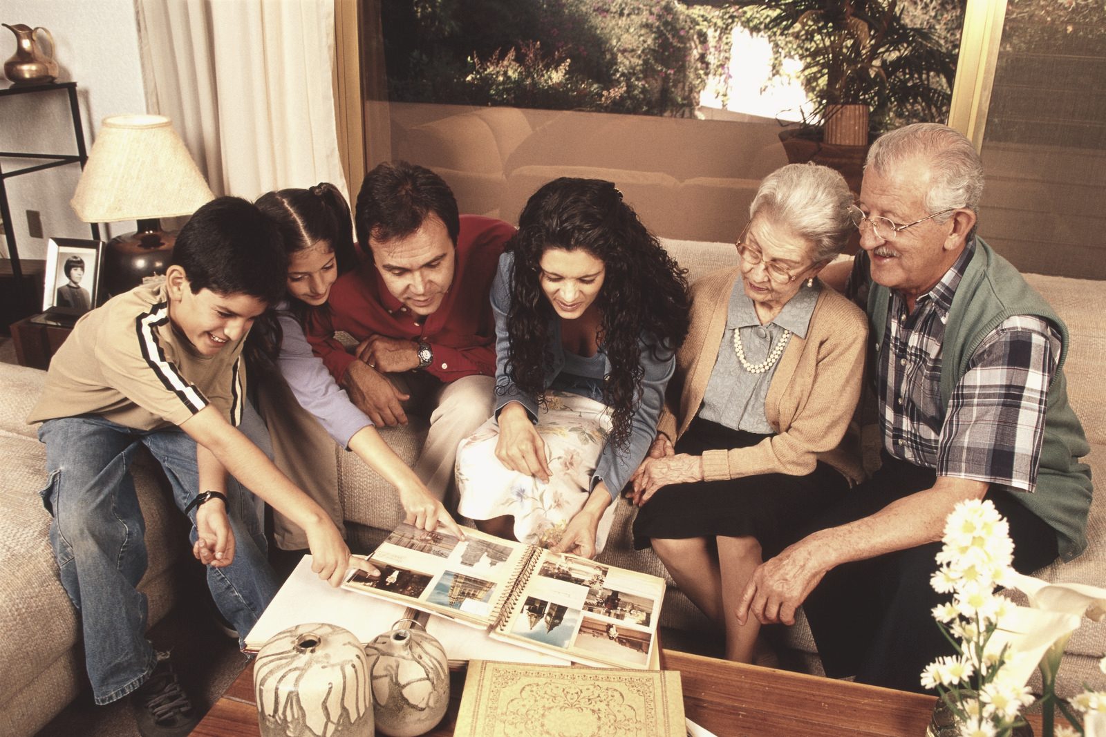 A multi-generational family gathered on the couch, sharing and enjoying an organized photo album together